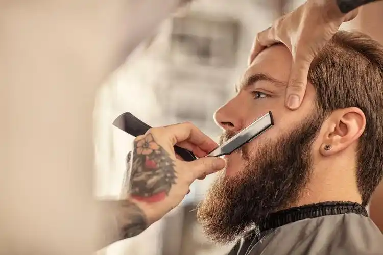 男子在理发店用剃刀刮胡子