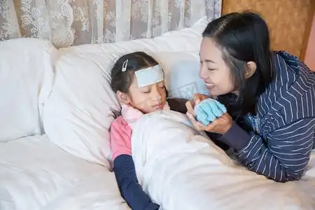 亚洲母亲照顾生病的女儿在床上