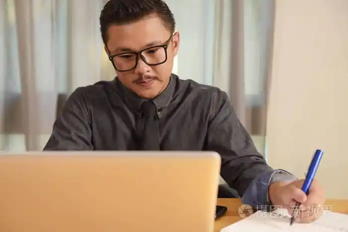 年轻人坐在他办公桌前在办公室里的肖像照片-正版商用图片0nh8pe-摄图