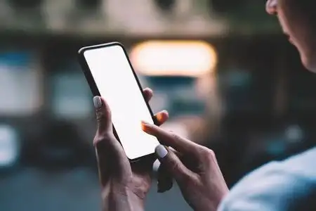 女人的手拿着大拷贝空间触摸屏的手机在户外与晚上散景城市的背景灯光