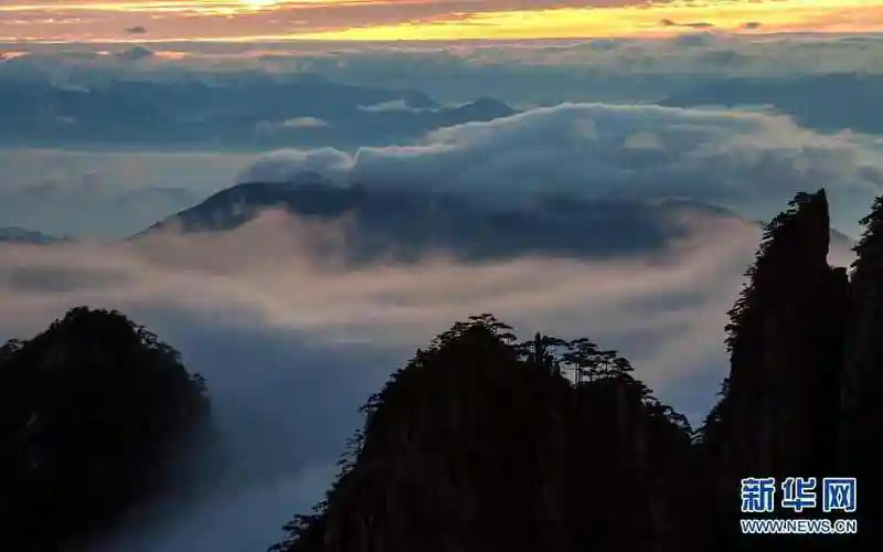 当日,黄山风景区晨曦初露,云遮雾绕,黛色的山峦,火红的朝阳与汹涌的