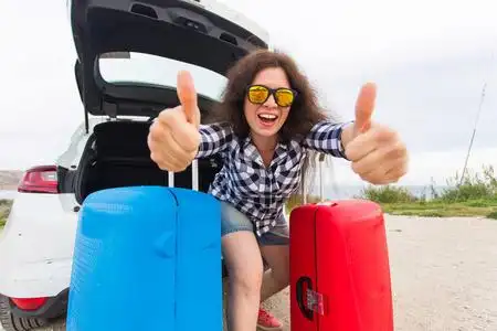 快乐出发站在汽车后面的年轻女子竖起大拇指, 准备出发.
