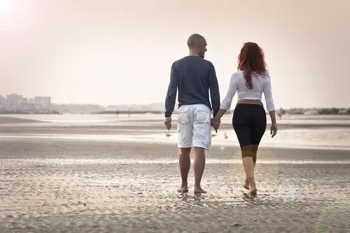 日落时,恋人手牵手 漫步在海滩上