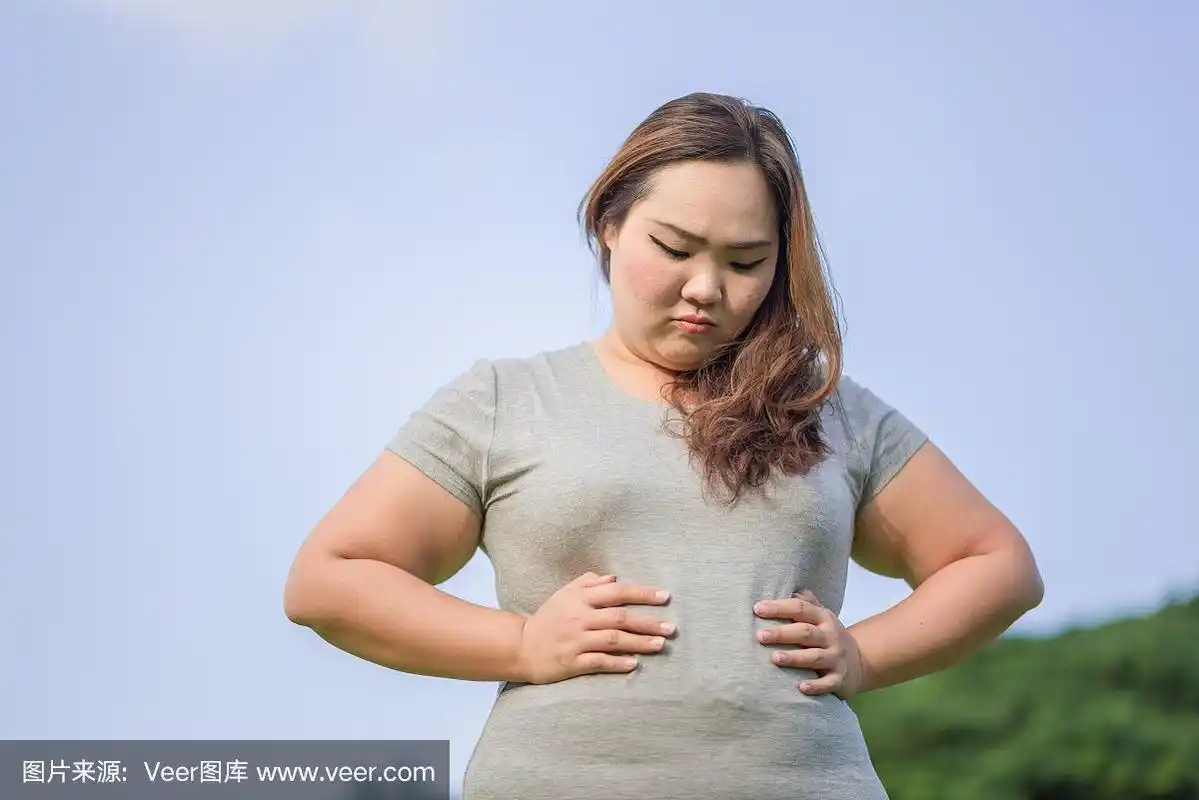 漂亮的胖女人在花园里检查她的大肚子