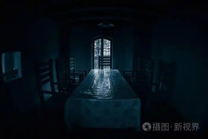 在黑暗的房间里放了一张大椅子的旧木桌.恐怖概念
