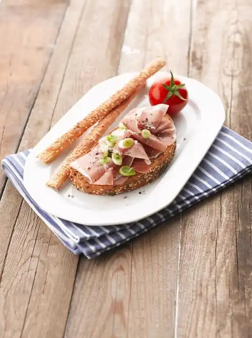 帕尔马火腿三明治,帕尔马火腿三文治配番茄在白板上.木制的表.