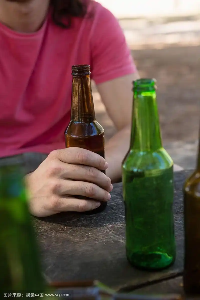 一个男人在公园里拿着啤酒瓶