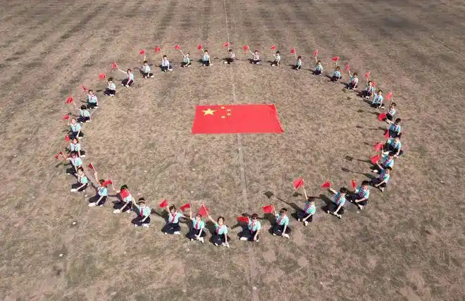 小学举行"我和国旗合个影"主题活动,少先队员摆出各种队形与国旗合影