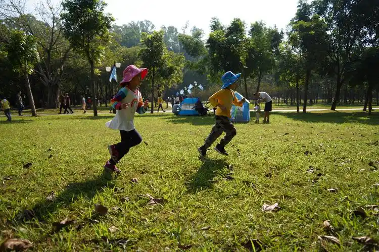 小朋友们抑制不住的在草地上奔跑,踢球.