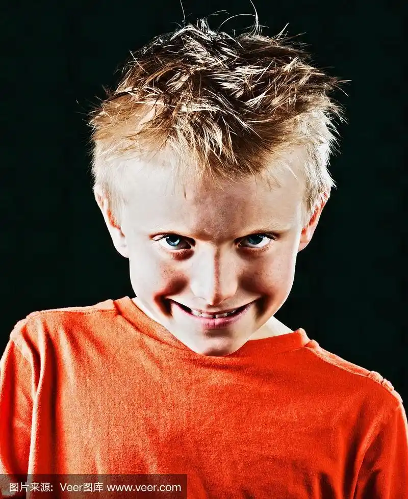 可爱的小男孩在黑色的背景下调皮地笑