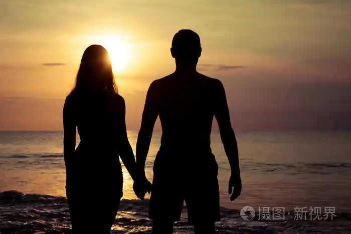 夫妻爱背光源剪影在海上日落的时候