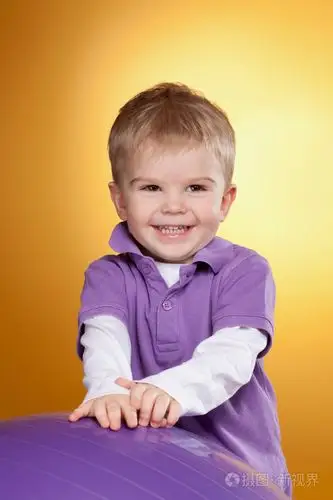 快乐的小男孩在紫罗兰色大球附近