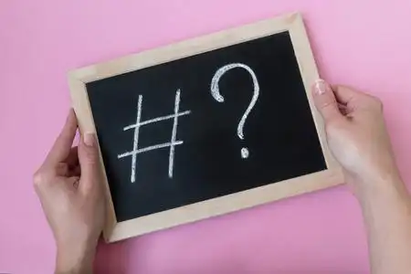 女性手拿着一块粉笔标签和一个问号写在黑板上.社会媒体推广理念照片