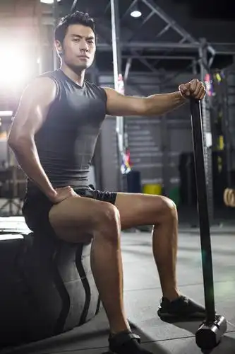 年轻男子坐在健身房的轮胎上休息