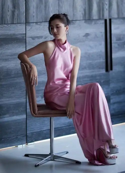 照片中,吴千语身穿一袭粉色无袖挂脖连衣长裙,裙摆长及拖地,脚蹬一双