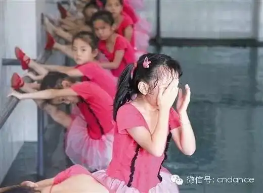 一个参加舞蹈兴趣班的女孩在练习压腿时痛得哭起来