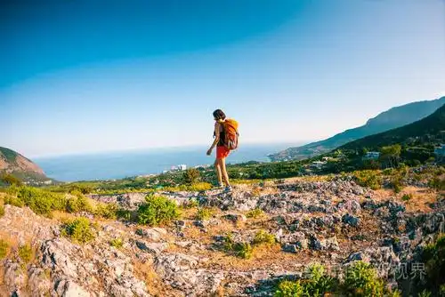 山顶上的女孩. 一个背着背包的女人站在岩石上. 爬到顶端.