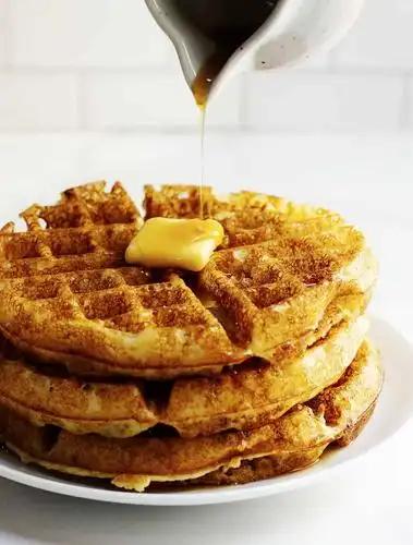 pouring syrup over belgian waffles