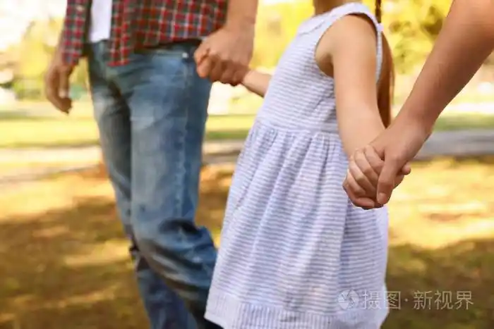 小女孩和她的父母手牵手在户外特写家庭周末