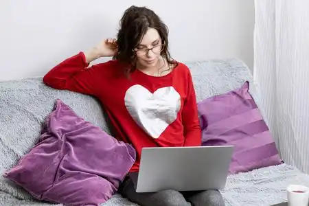 女人躺在沙发上看着笔记本电脑.在家休息的女孩照片