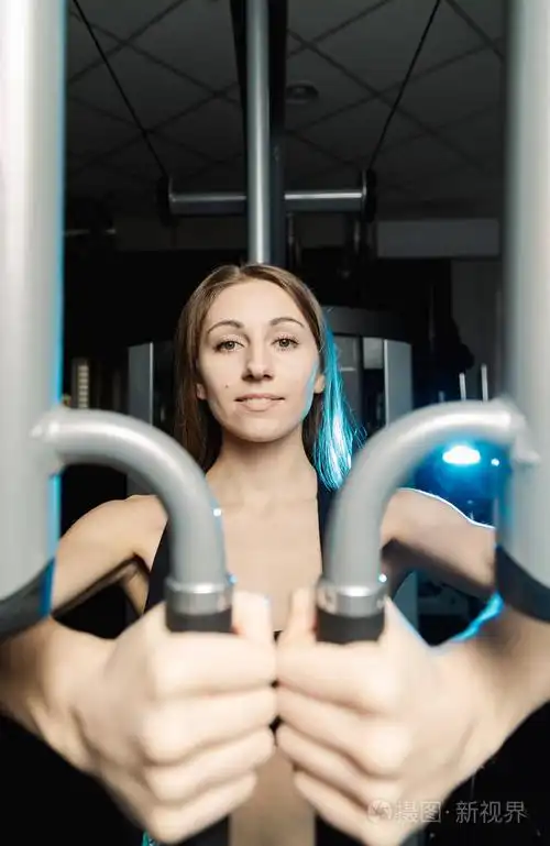 活跃美丽的健身模型女孩训练在健身房的模拟器胸肌