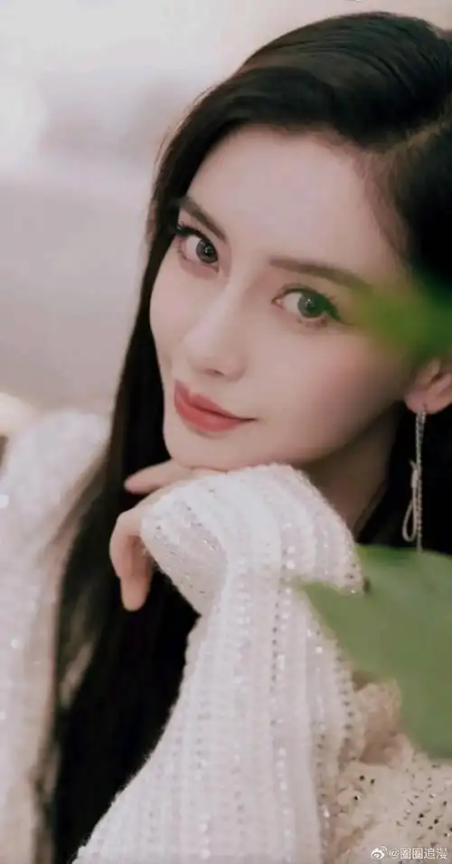 照片中,杨颖身穿白色仙女裙,外搭针织开衫,她俏脸甜美可人,乌黑的黑长