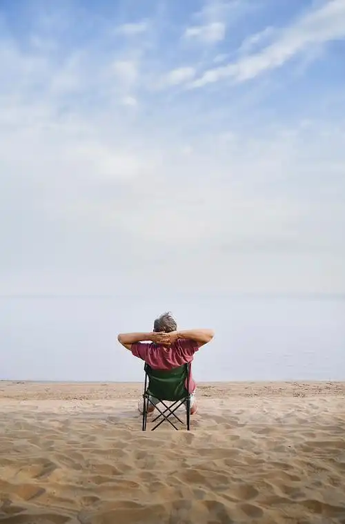 一名男子坐在海滩的折叠椅上放松图片下载