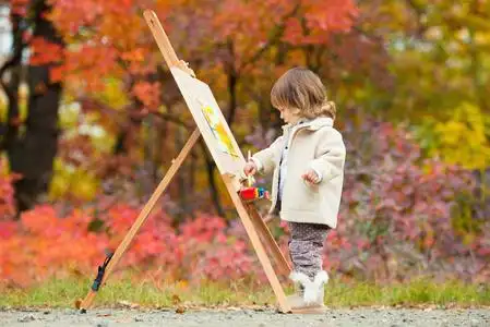 秋天的女婴画在秋叶公园, 小孩画画, 孩子们的创造力照片