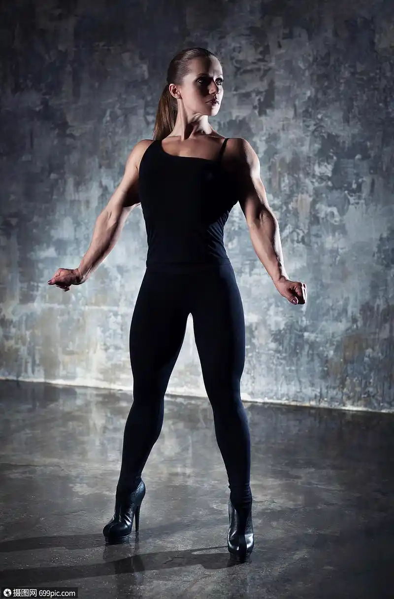 强壮的女健美运动员穿着黑色的衣服站墙上的背景上身体女的