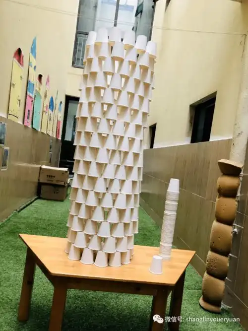 你们踮着脚和搭建的纸杯比较,同时也邀请老师来比一比,看看谁更高?