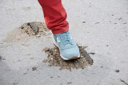 男足在运动鞋轮胎轨道上的动物粪便.脚踩着一块干牛粪.