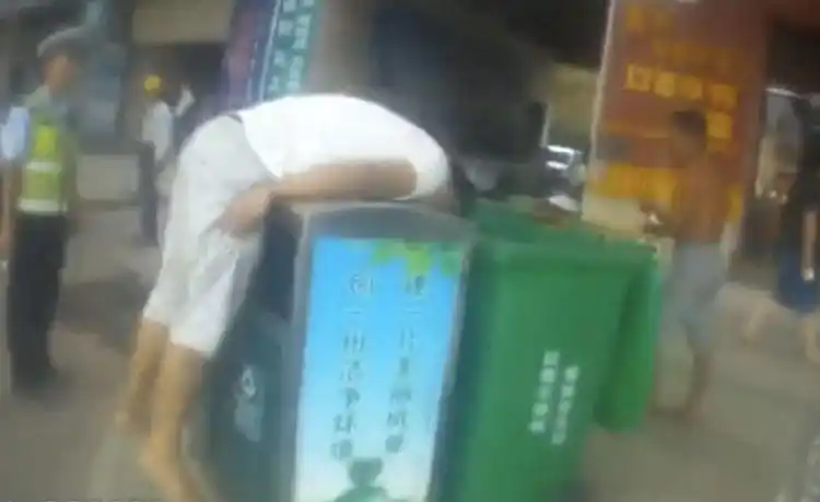 男子坐街上抱警察大腿,站起身又钻进垃圾桶,警察直接带走了他