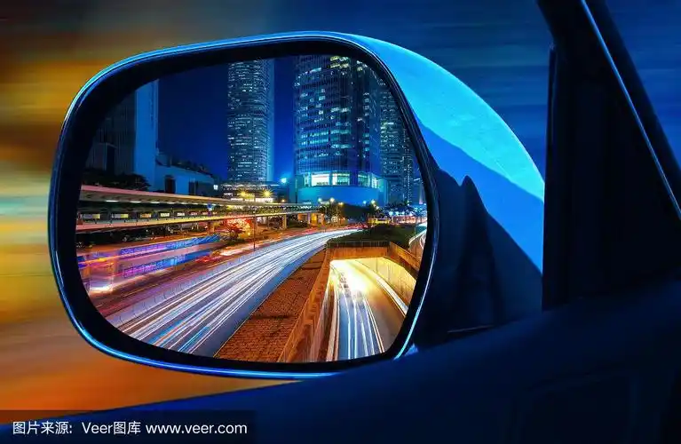 近距离的后视镜汽车在晚上全速与摩天大楼的大都市