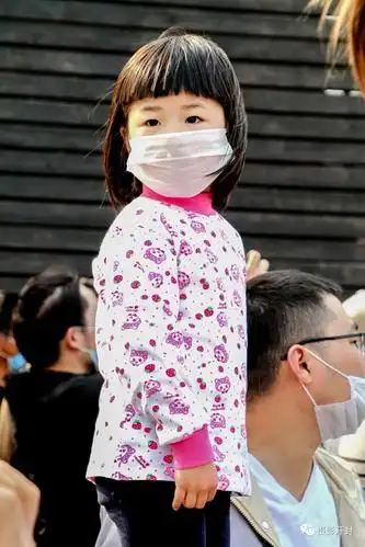 一个戴口罩的小女孩站在父亲旁边向远处观望.