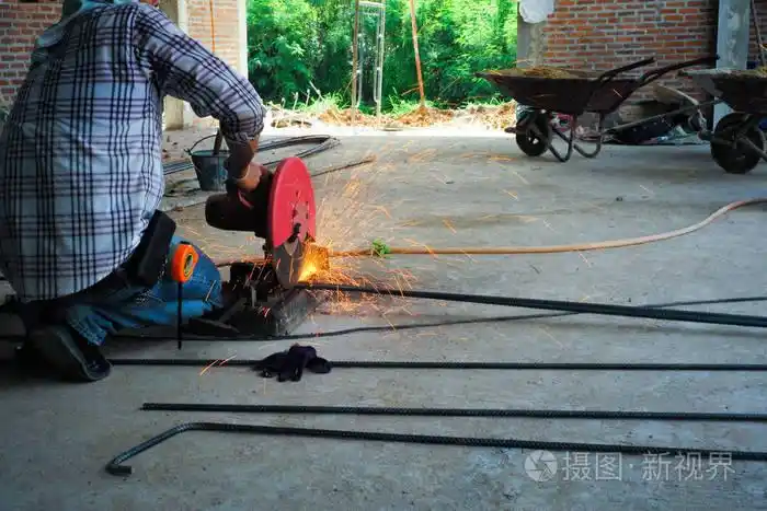 工人在施工现场用电气切割机切割钢筋从钢制切割机上射出闪闪发光的光