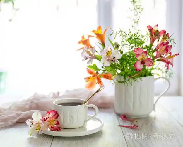 白色杯子在桌子上的茶附近的花