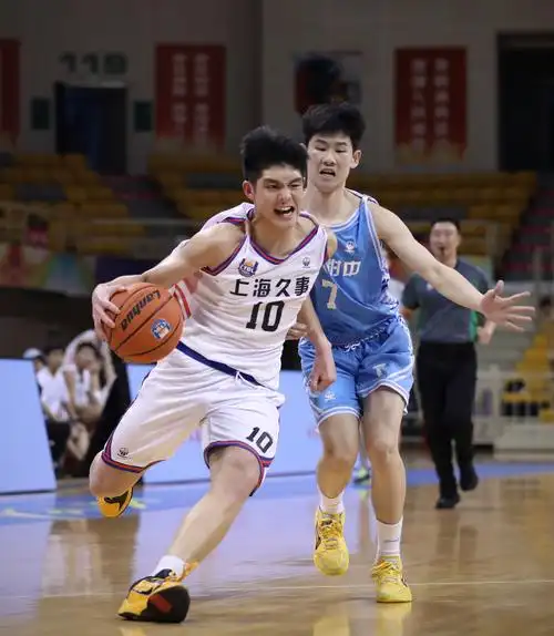 6月30日,上海久事队球员王子恒(左)在比赛中带球突破.