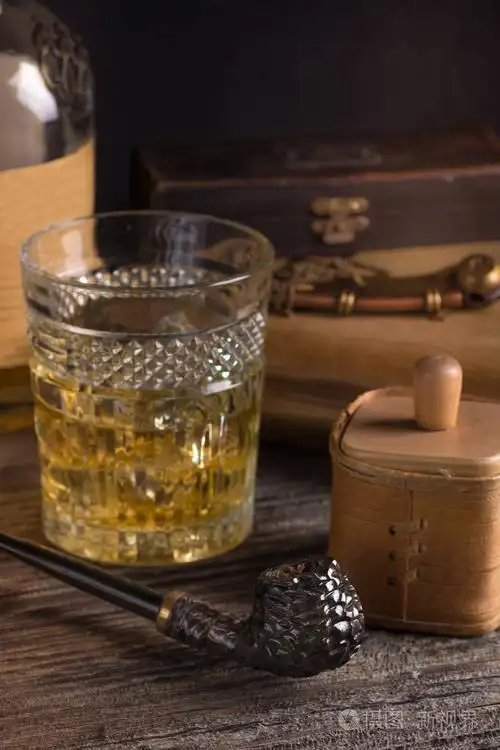 烟草在木桌上的高高的玻璃上刻着深褐色的烟烟斗和威士忌照片-正版