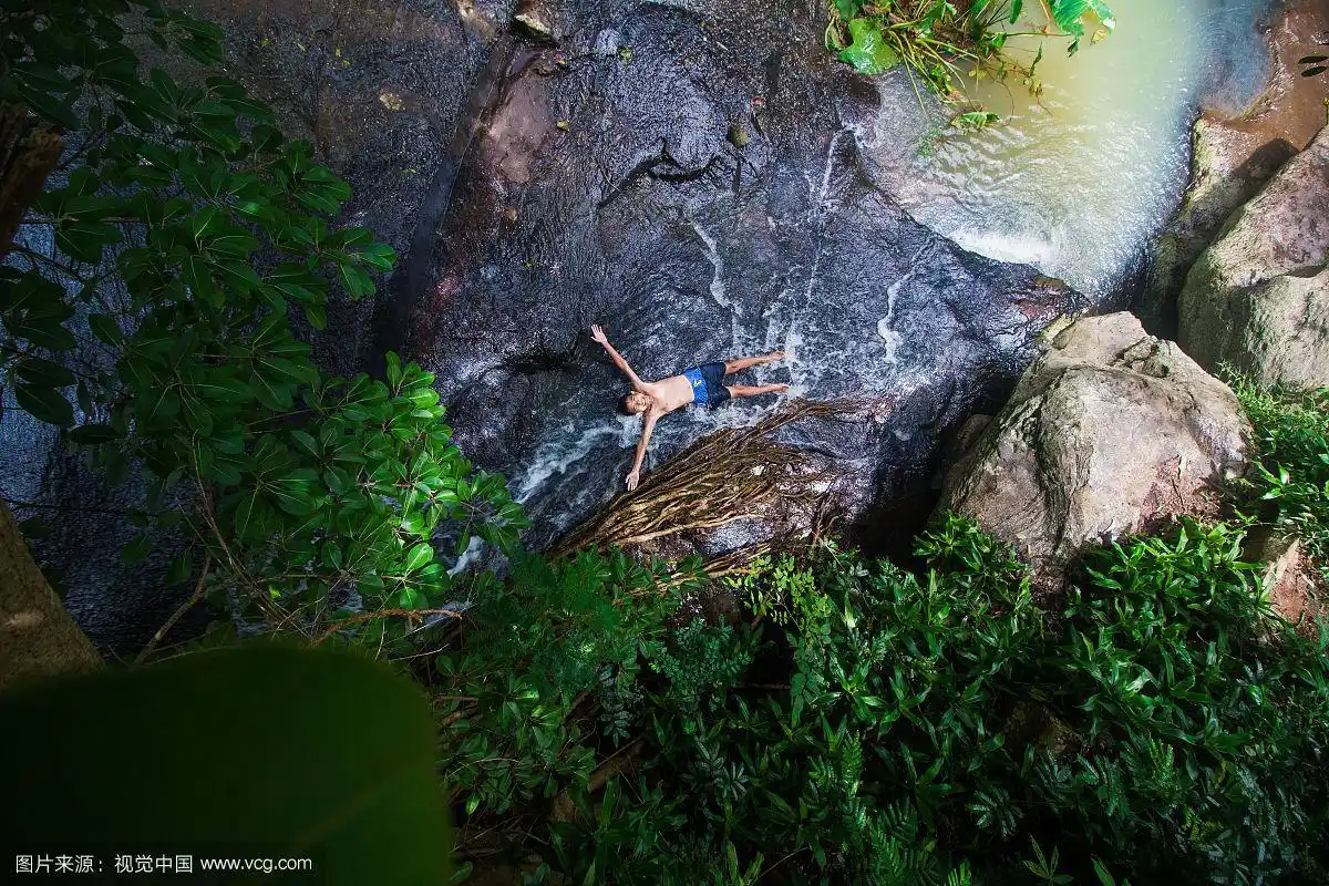 赤膊男孩躺在森林池塘边的岩石上