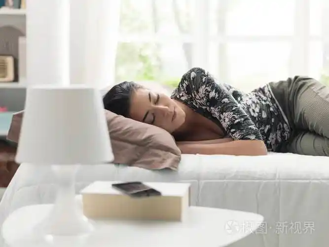 年轻漂亮的女人躺在床上休息下午的生活方式和放松的概念