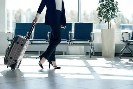 机场里背着行李的年轻女商人的双腿.出差照片
