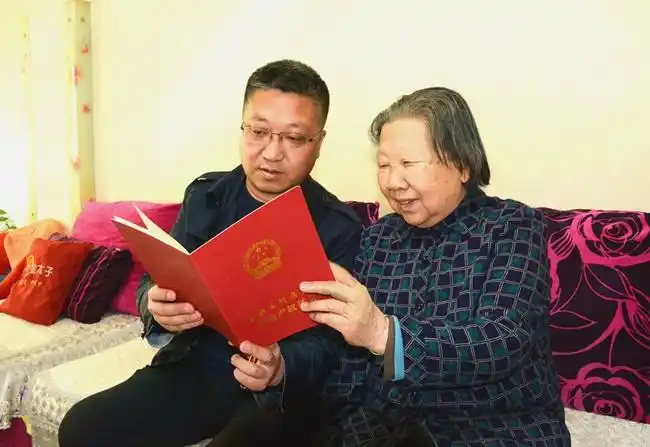 拿到"大红本",吃下"定心丸".李海金(左)与母亲一起翻看不动产权证.