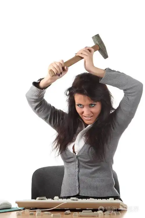 愤怒的女孩用锤子敲打键盘