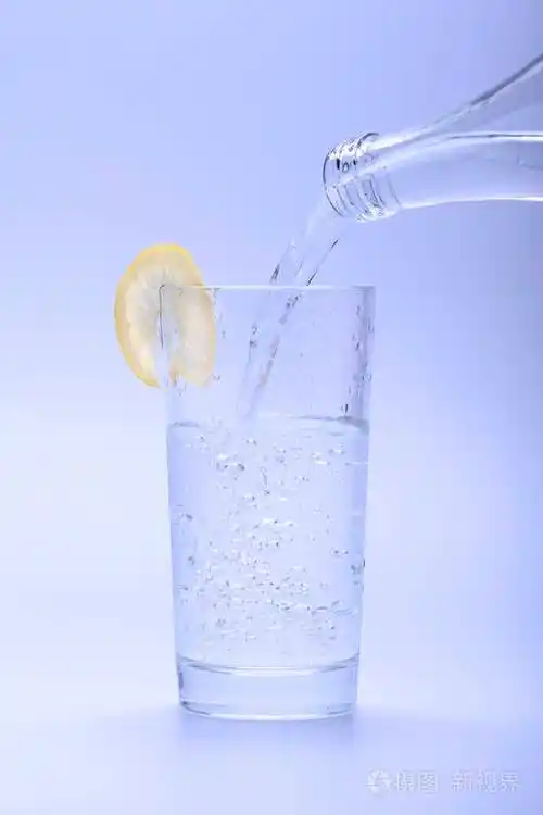 冰冷的淡水从瓶子里倒入一杯柠檬水中
