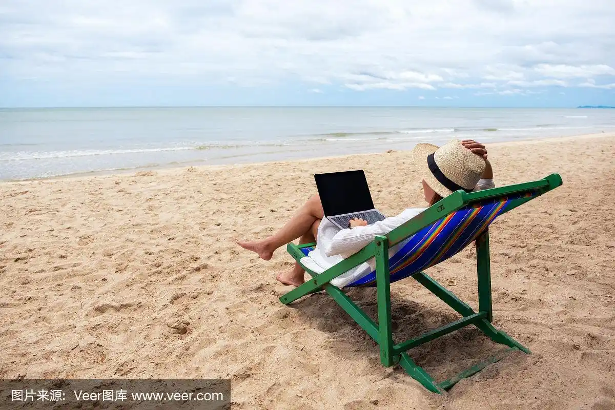 一个女人躺在沙滩椅上使用笔记本电脑