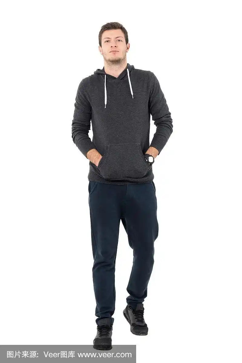 正面的观点,自信的年轻人在运动服行走与手在口袋.