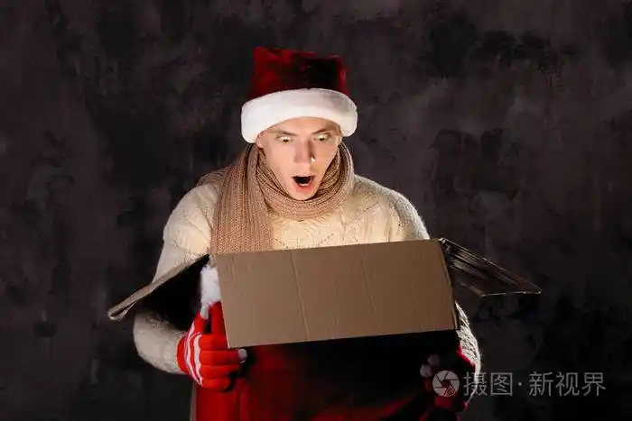 圣诞礼物概念戴圣诞帽的人给你带礼物有魅力的男人拿着盒子圣诞节和