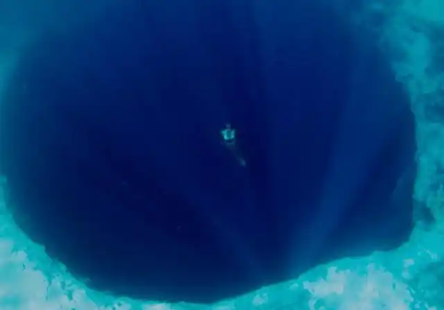 一名潜泳者从深海的蓝洞上游过.