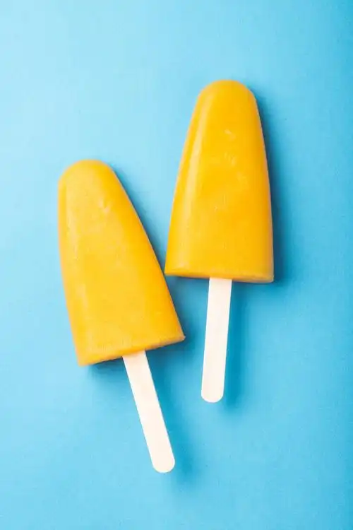 橙色的冰棒和果汁在蓝色的背景