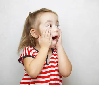 惊讶的小女孩张开嘴和双手脸颊照片